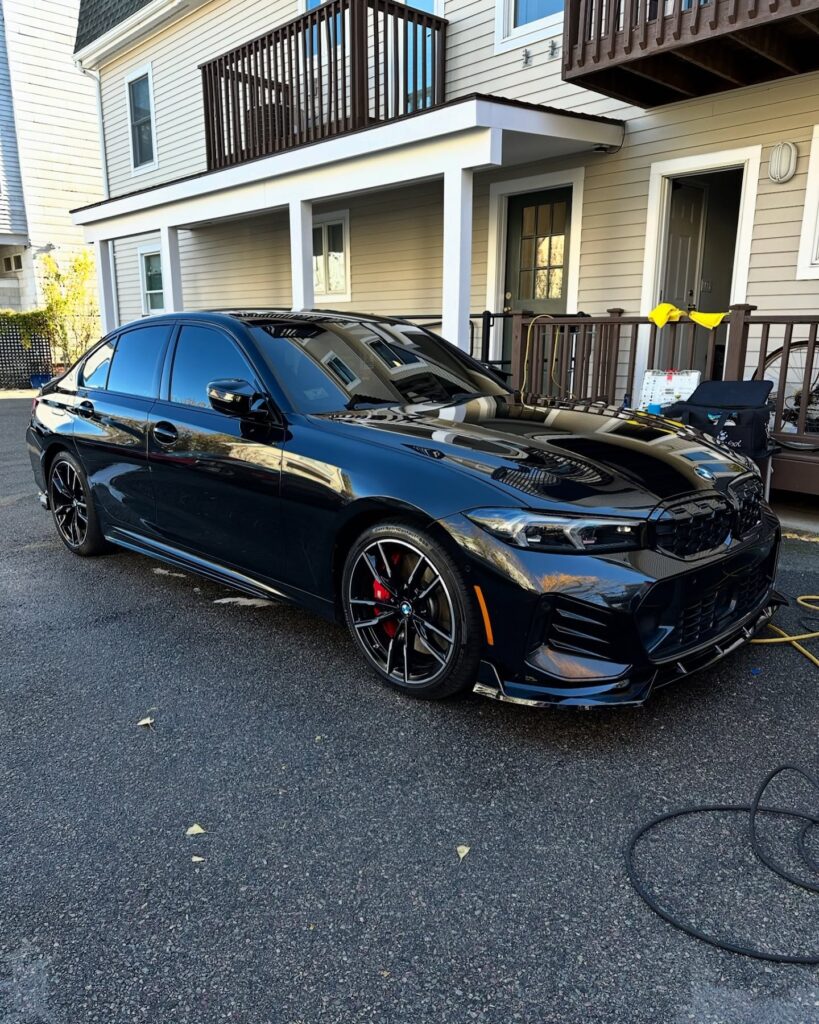 Black BMW sedan parked on a driveway with its body panels, grille and alloy wheels visible