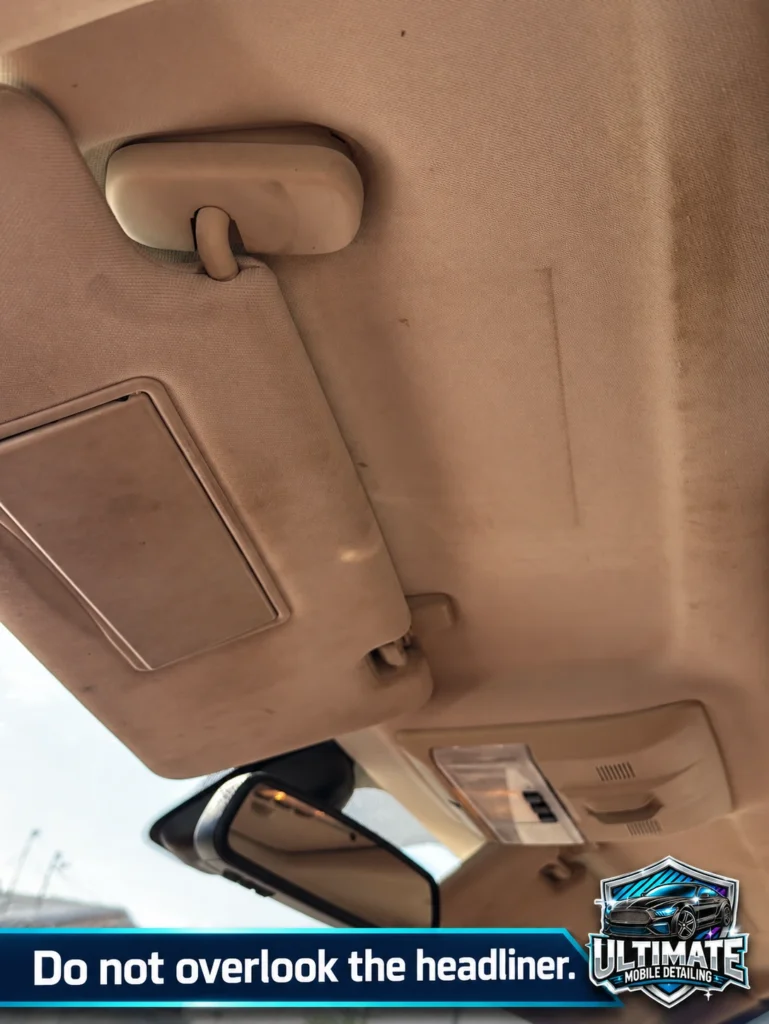 Visible marks on beige roof-lining fabric beside the sun visor and its mounting point