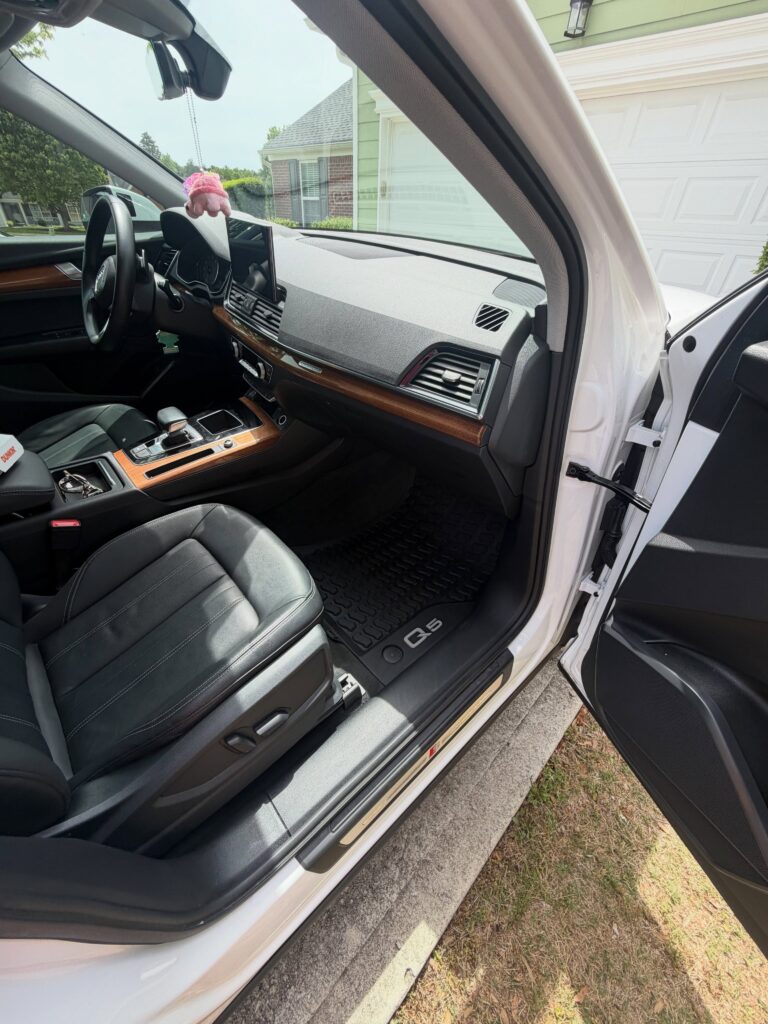 Black leather front seating and a wood-trimmed center console in a vehicle interior.