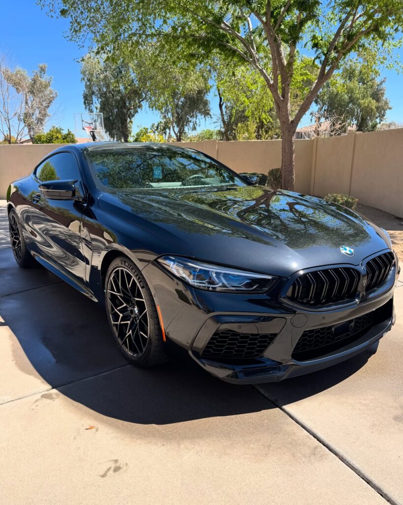Dark BMW coupe viewed from the front corner, with its headlamp, grille and bumper visible