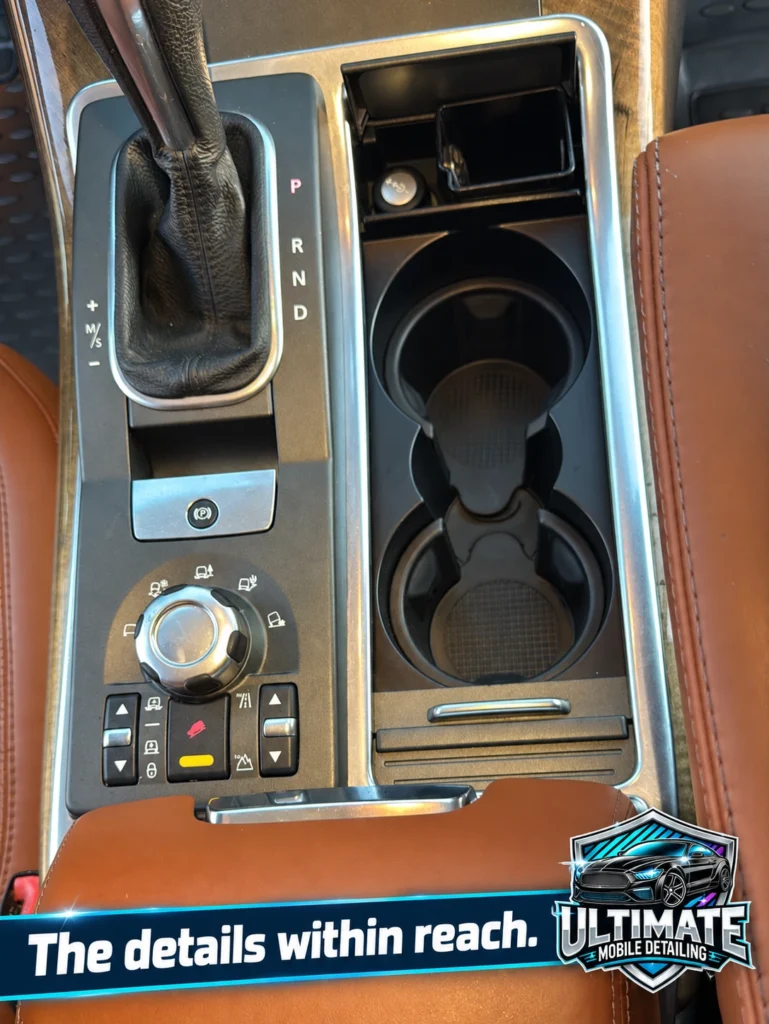 Overhead view of cupholders and gear selector between brown leather console trim