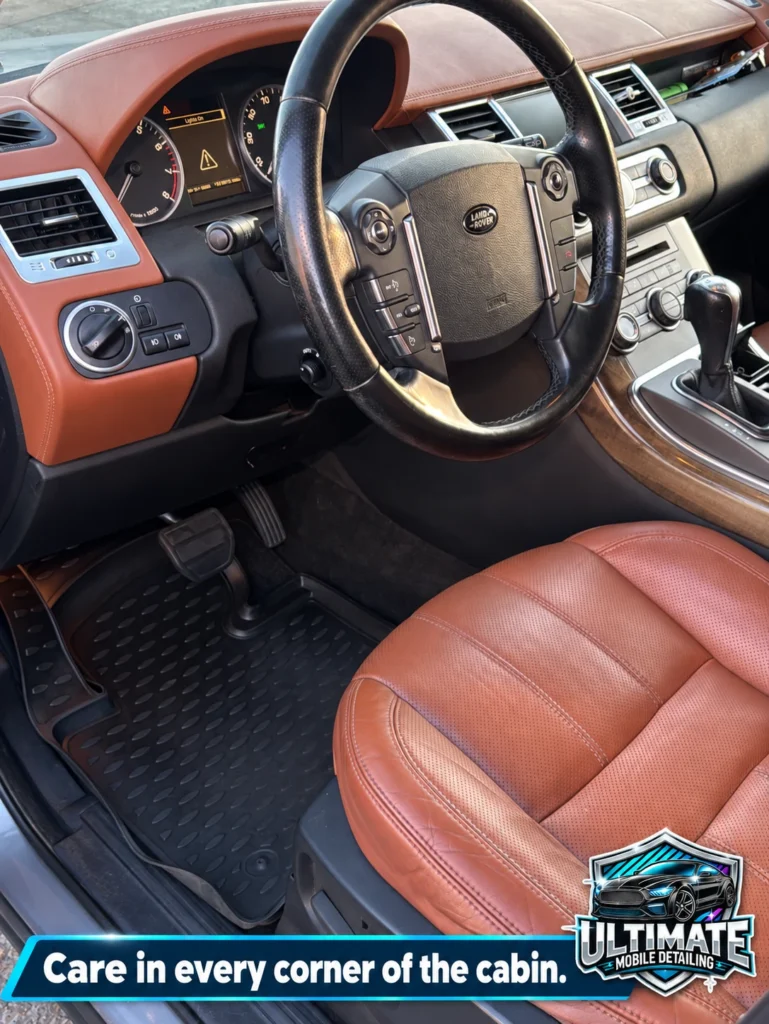 Range Rover driver area with brown leather seating, steering wheel, dashboard and rubber floor mat